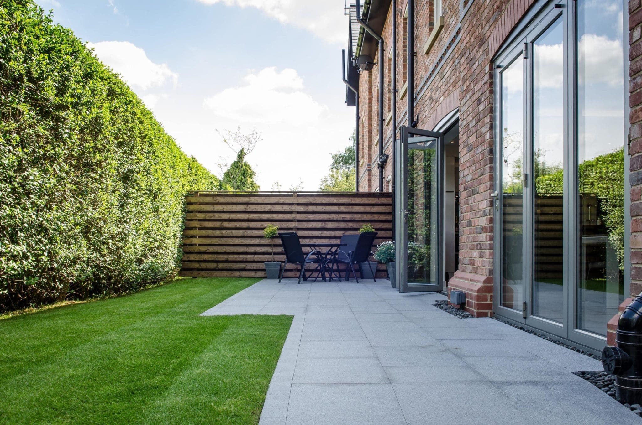 a patio with a table and chairs next to a brick building.