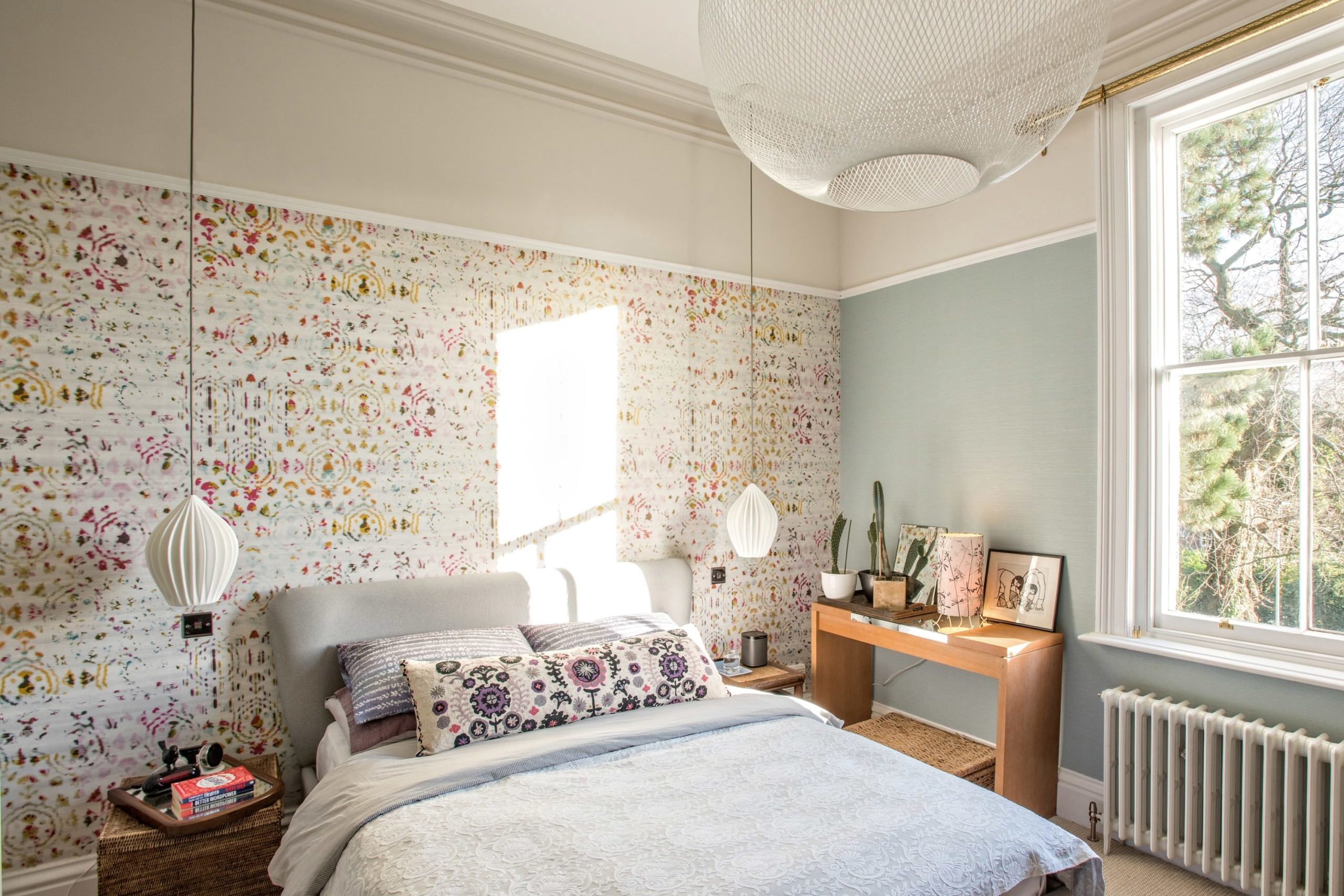 a bedroom with floral wallpaper and a white bed.