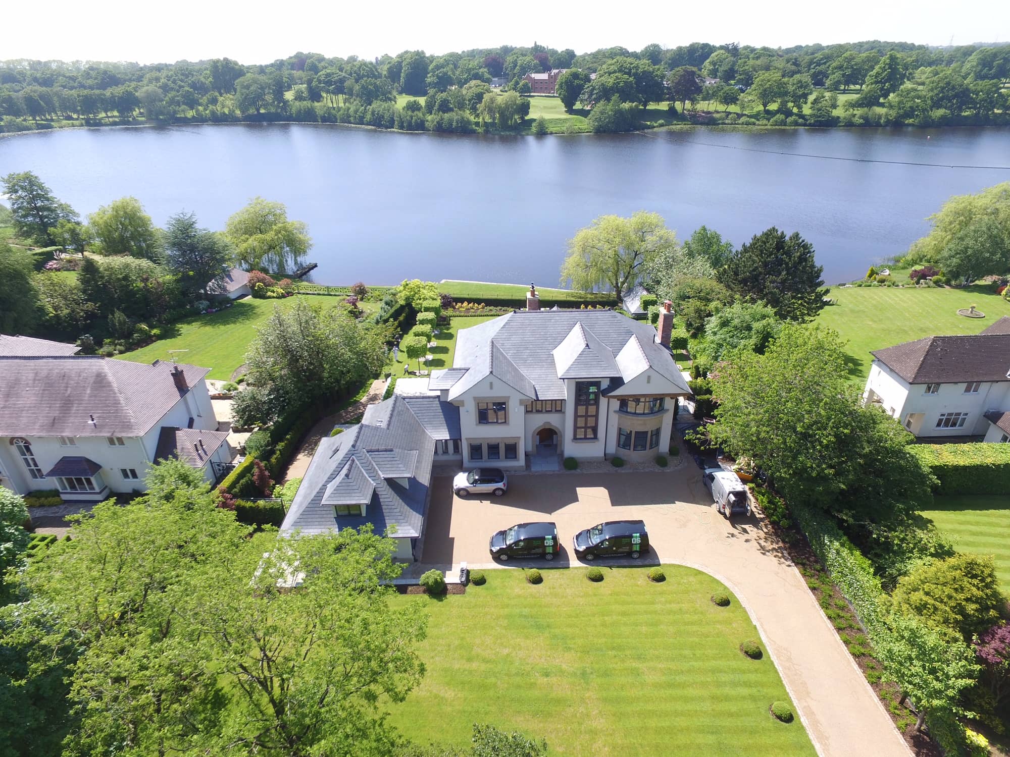 an aerial view of a large house with a lake in the background.