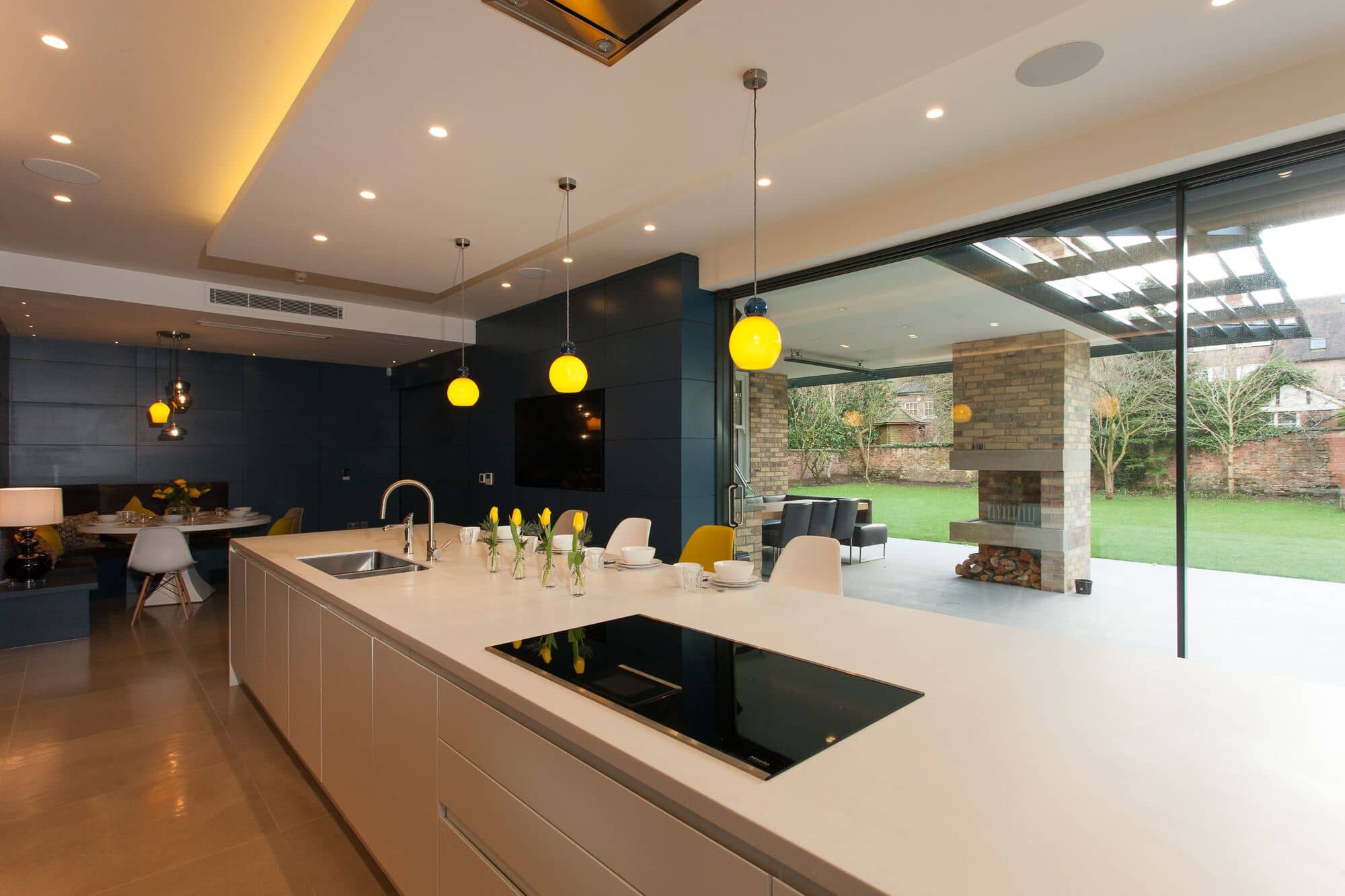 a kitchen with a large white counter top next to a living room overlooking a garden.
