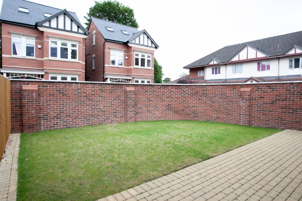 a brick wall with a green lawn in front of it.