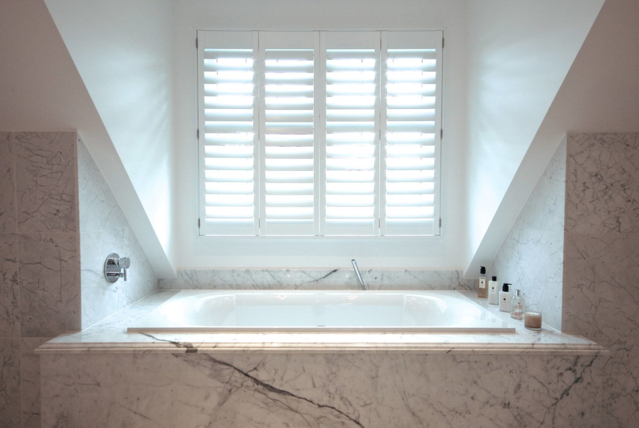 a bathroom with a large white bathtub under a window.