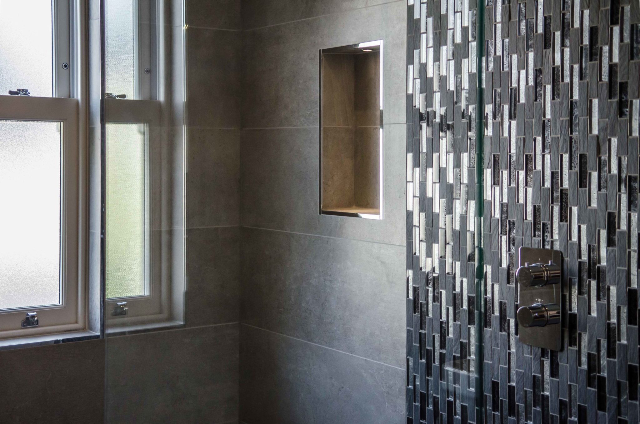a bathroom with a tiled shower and a window.