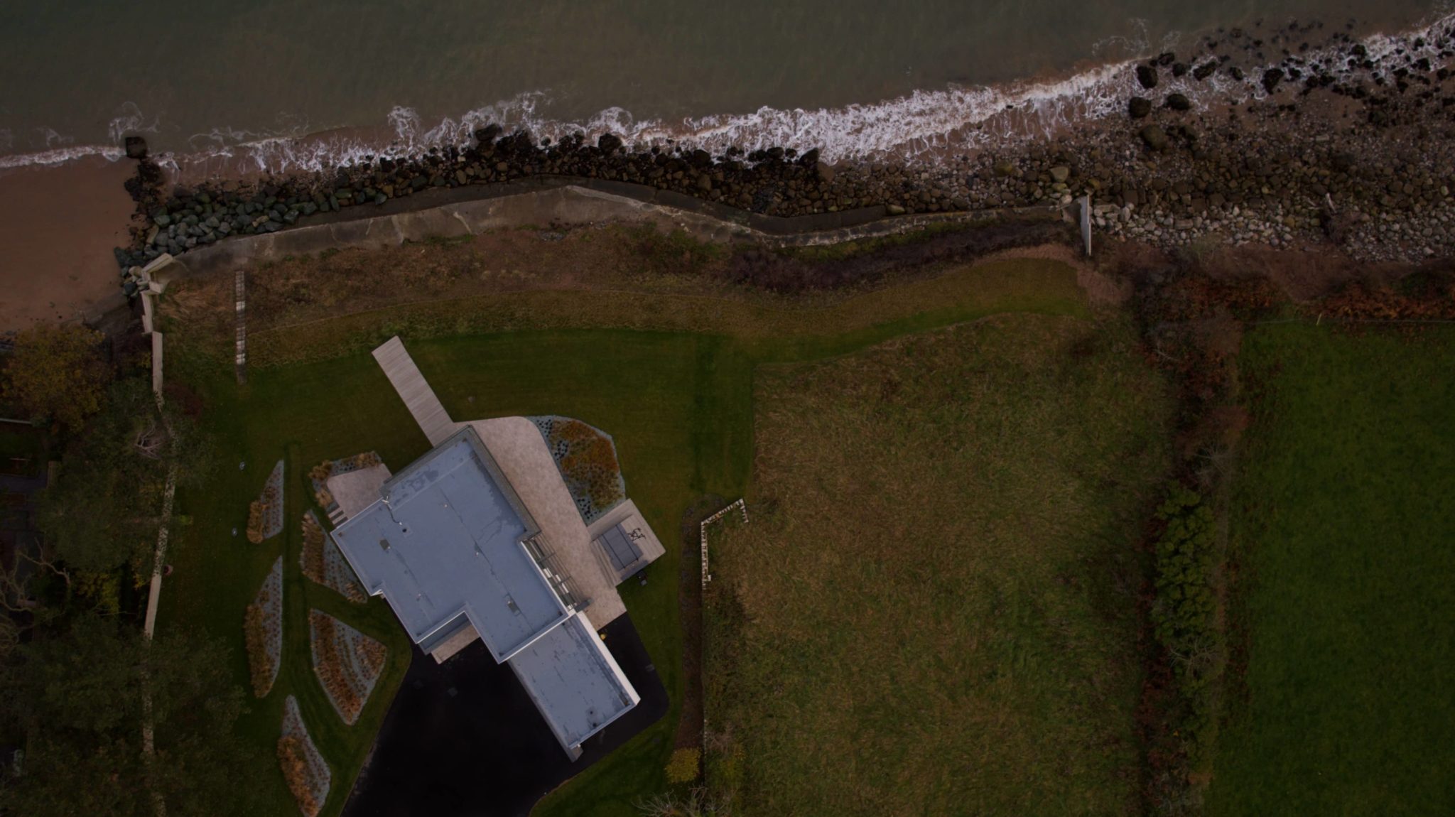 an aerial view of a house next to a body of water.