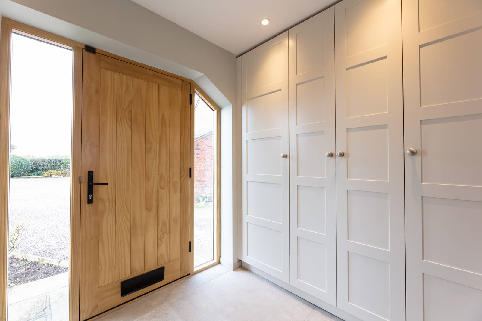 A hallway with a wooden door and white cupboards.