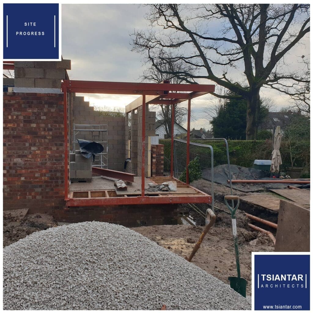 A construction site with a brick wall and a pile of gravel showing site progress.