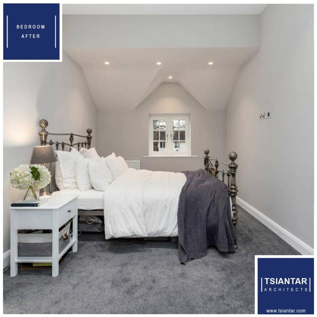 A refurbished bedroom, part of a home renovation, featuring a white bed with pillows, a blue throw blanket, bedside tables with lamps, under a sloped ceiling with a window.