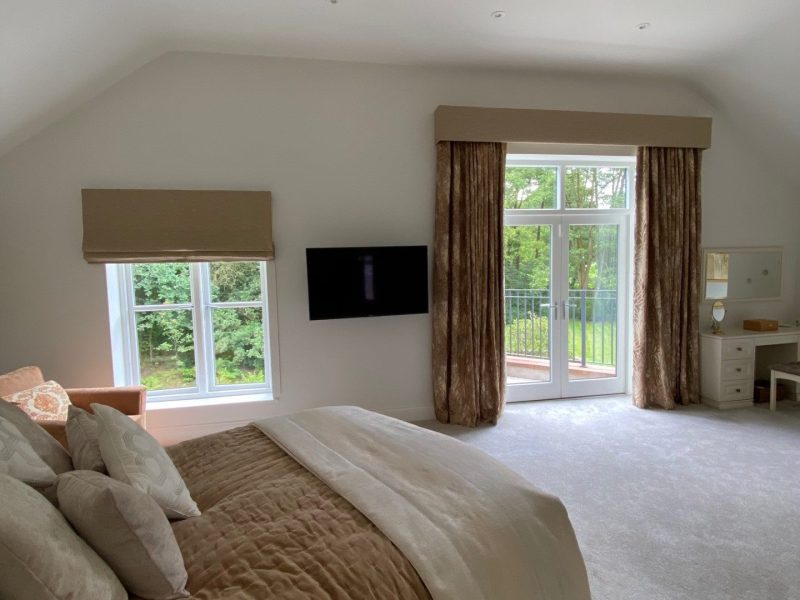 A large bedroom with a tv and large windows.
