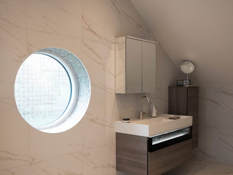 A white bathroom with a round window.