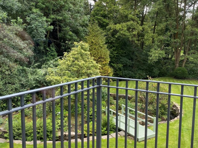 Wrought iron railings on a balcony overlooking a garden.