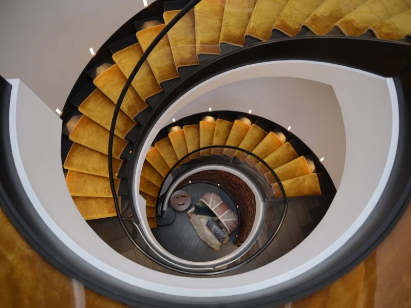 a spiral staircase in a building with yellow carpet.