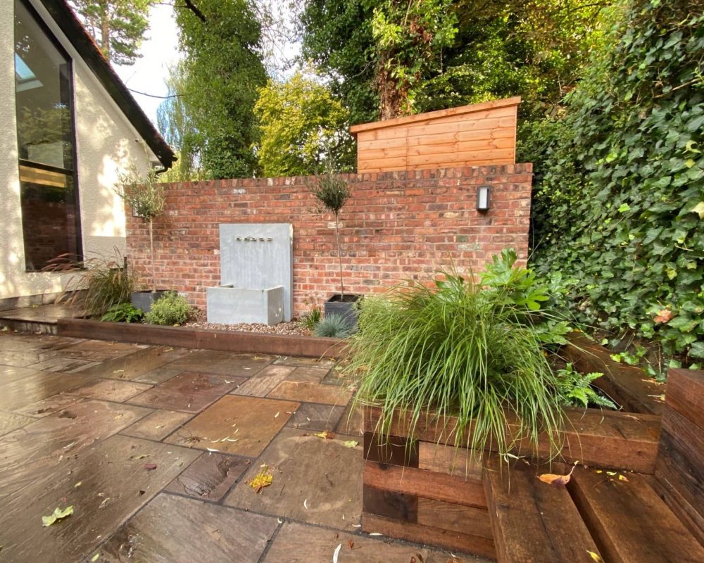 a backyard with a brick wall and wooden decking.