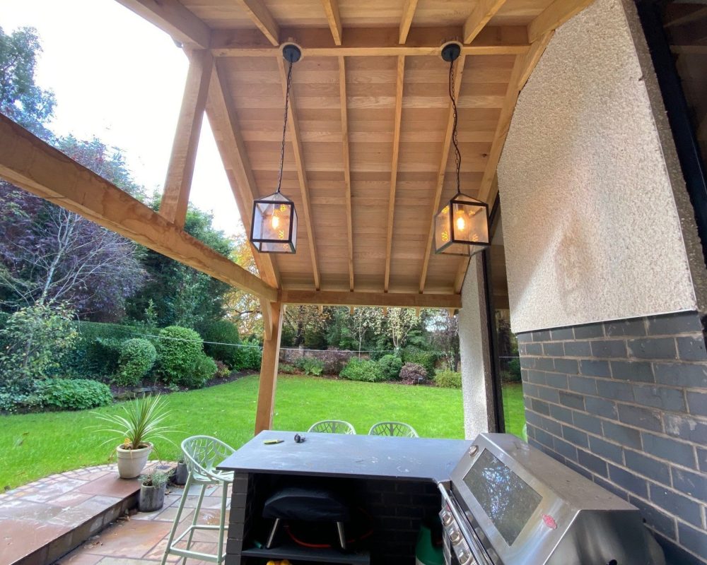 a patio with a grill and lights hanging from the ceiling.