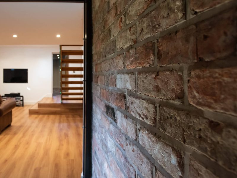 a living room with a brick wall and stairs.