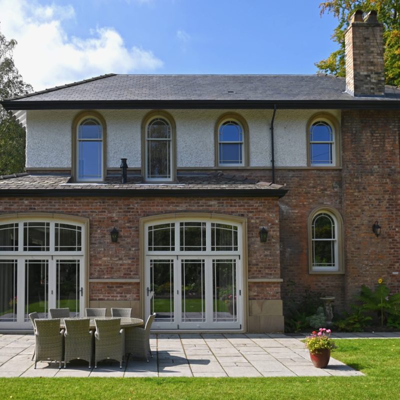 A large brick house undergoing renovation with a patio area.